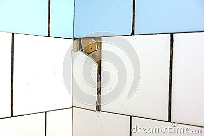 White and blue tiles on the wall. Old and broken tiles require replacement. Abstract background Stock Photo