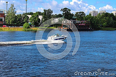 White boat sailing on the river against the background of a floating restaurant, trees and a blue sky with clouds. St. Petersburg Editorial Stock Photo