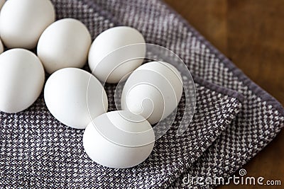 White eggs on a grey and white checkered kitchen towel upon a wooden table Stock Photo