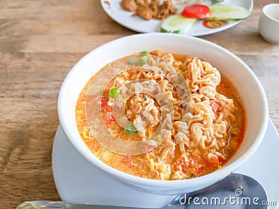 A white bowl of delicious instant noodle curry`s tast cooked on wooden table, closeup image with copy space Stock Photo