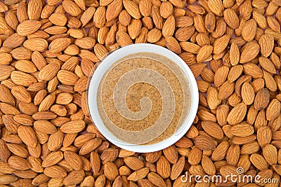 Bowl of almond butter surrounded by raw fresh almonds Stock Photo