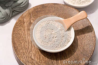 White bowl with gray cosmetic clay on wooden tray - mineral powder Stock Photo