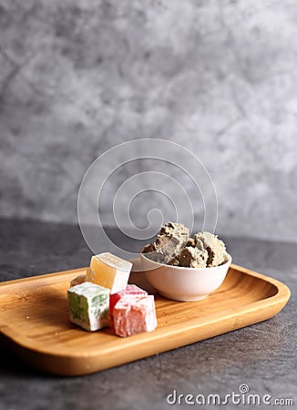 White bowl of halva and a pile of Turkish delight on gray background Stock Photo