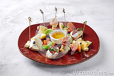 White bread tapas with ham and cucumbers, with tomato sauce and cheese, lying on a plate Stock Photo
