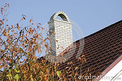 White brick chimney on the brown roof of the house Stock Photo