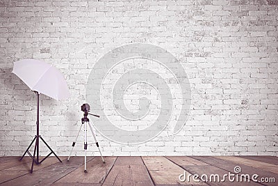 White brick wall in a photo studio. An umbrella for illumination and a tripod for a camera. Empty copy space Stock Photo