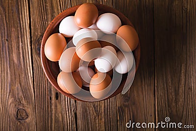 White and brown eggs in a ceramic bowl on a wooden background. Rustic Style. Eggs. Easter photo concept. Stock Photo