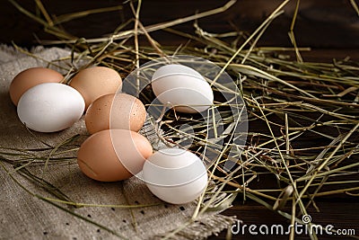 White and brown eggs on straw and wooden dark background Stock Photo
