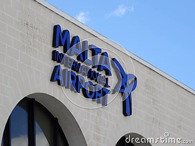 The white building of the Malta International Airport with arch windows and a big blue banner sign on the wall. Airport is close Editorial Stock Photo