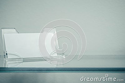 Acrylic paper stand for a blank card, business card stand on glass shelf . Flyer leaflet white paper card template design. Stock Photo