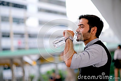 White business handsome man drink water from bottle during day time in the city for refreshment Stock Photo