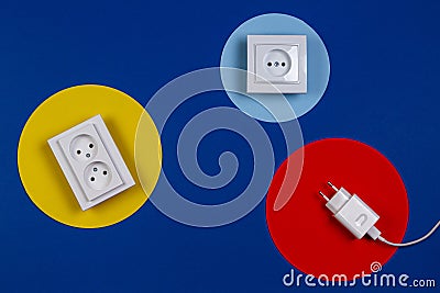 White cable and electrical sockets on geometric yellow red blue navy color background Stock Photo