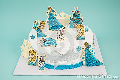 White cake with Elsa cake decorations isolated on the blue background Editorial Stock Photo