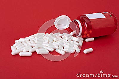 White calcium pills pouring out of red bottle Stock Photo