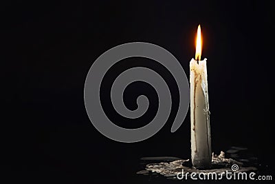 White candle burns in the dark on a black background in smoke Stock Photo