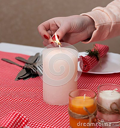 The white candle stands on the table. Festive composition with Lighted candles. Christmas table decoration. A beautiful table. Stock Photo