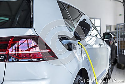 A white car that is charged with electricity. A new generation of cars Editorial Stock Photo