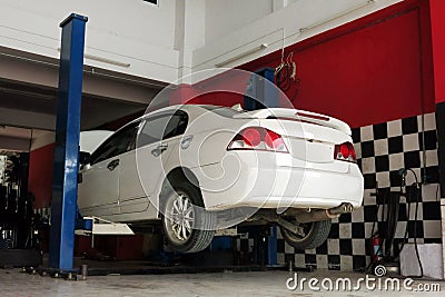 A white car is lifted up for the repairing process at the garage Editorial Stock Photo