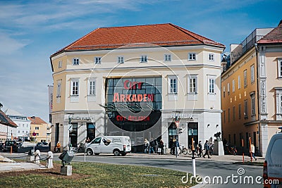 White car is parked in front of the entrance of the city Arkaden with people walking on the sidewalk Editorial Stock Photo