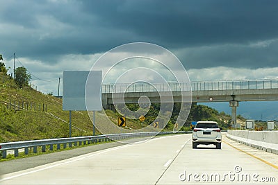 White car on the road. Highway traffic. Car on the asphalt under cloudy sky Stock Photo