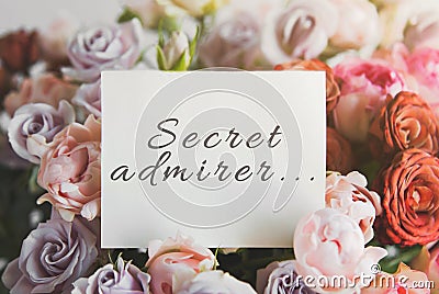 White card for a bouquet with the inscription secret admirer in a bright beautiful bouquet of roses Stock Photo