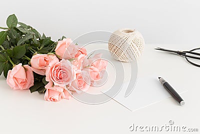 White card, bouquet of pink roses and a twine on a white table Stock Photo