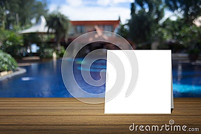 White card put on wooden desk or wooden floor on blurred swimming pool at resort background.use for present your product Stock Photo
