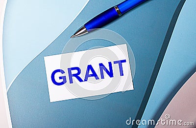 White card with text GRANT and a blue pen on a blue, blue and pink background Stock Photo