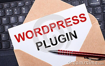 White card with the text WORDPRESS PLUGIN in a craft envelope on a work desk with a modern laptop keyboard and burgundy pen. Flat Stock Photo