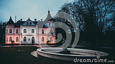 The White Castle - music school and fountain in Baldone, Latvia. The castle is illuminated in the dark in the colors of Latvia - Stock Photo