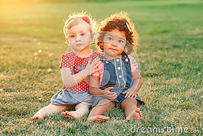 White Caucasian and latin hispanic babies hugging outside in park. Stock Photo