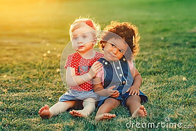 White Caucasian and latin hispanic babies hugging outside in park. Stock Photo