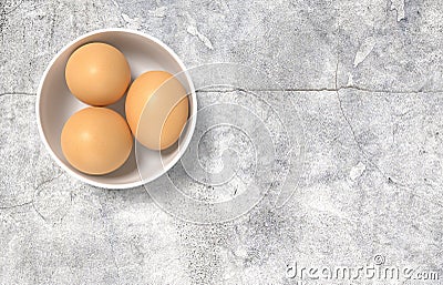 White ceramic bowl ful of eggs. Placed on concrete table. Stock Photo
