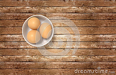 White ceramic bowl ful of eggs. Placed on wooden table. Stock Photo