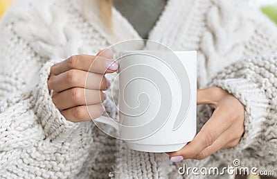 White ceramic mug mockup. Woman in Sweater Holding a Warm Cup of Coffee. Copy space for your print Stock Photo