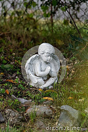 White cherub angel sitting in garden praying Stock Photo