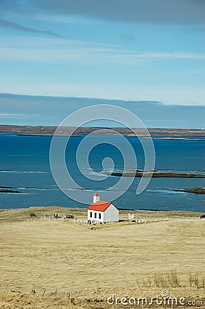 White church, turquoise sea, hayfield, Iceland Stock Photo