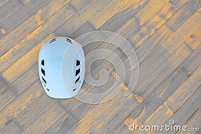 White climbing helmet also used in alpine or industrial constructions on wooden background with diagonal timber planks. Stock Photo