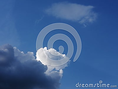 A white cloud and dark cumulus floating against a clear blue sky Stock Photo