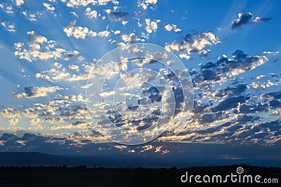White clouds in the blue sky over the mountains, dawn. The sun`s Stock Photo