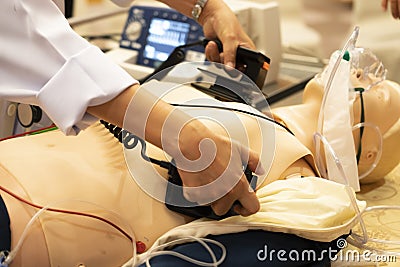 A white coat physician perform defibrillationon a doll during AC ACLS training Stock Photo