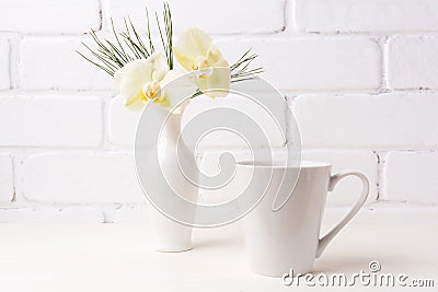 White coffee latte mug mockup with soft yellow orchid in vase Stock Photo