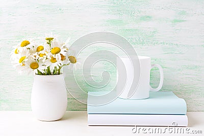 White coffee mug mockup with white field chamomile bouquet in ha Stock Photo