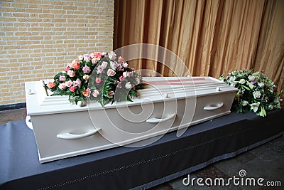 White coffin with pink sympathy flowers Stock Photo