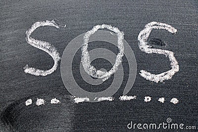 White chalk hand drawing in SOS abbreviation of save our soul/ship or sibling over shoulder on black board background Stock Photo