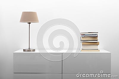 White commode with lamp and books in bright interior Stock Photo