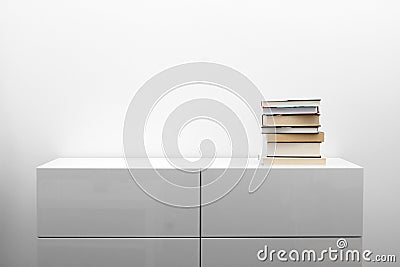 White commode with stack of books in bright minimalism interior Stock Photo