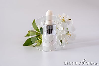 White cosmetic skincare dropper bottle packaging cherry blossoms flowers on white background Stock Photo