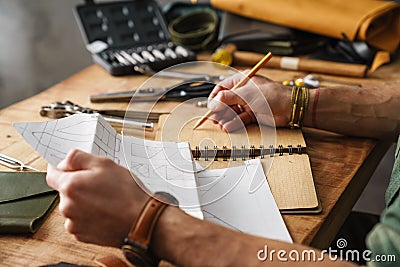 White craftsman drawing while working with leather Stock Photo