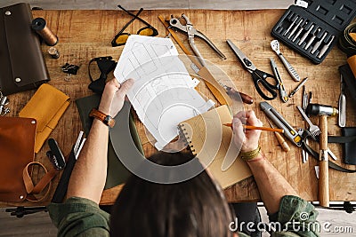 White craftsman drawing while working with leather Stock Photo